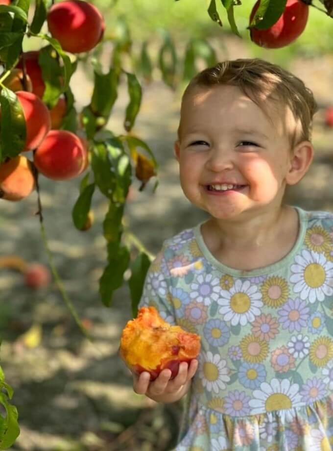 All smiles with juice dripping down the chin of this satisfied customer who just picked her own Bennett Peaches